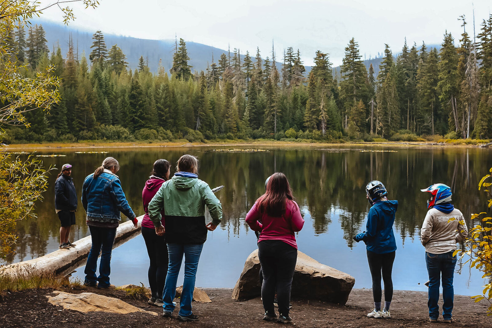 Women gathered at the edge of the lake among the pines